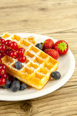 Frische Waffeln mit Puderzucker und Beeren auf einem Tisch