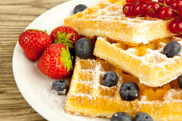 Frische Waffeln mit Puderzucker und Beeren auf einem Tisch