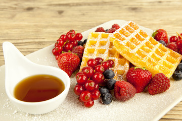 Frische Waffeln mit Puderzucker und Beeren auf einem Tisch