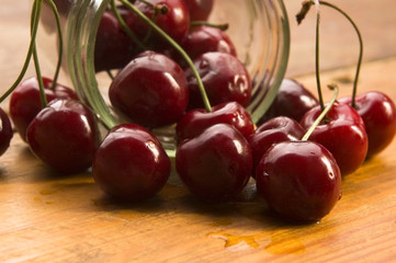 Cherry in glass jar isolated on the wooden background
