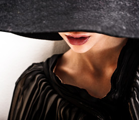 girl in black hat touching face and lips