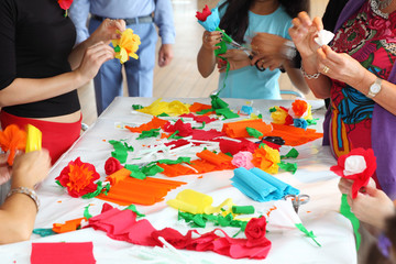 Hands of people standing near table make artificial flowers