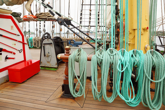 Many ropes, windlass and rigging on an ship with wooden deck