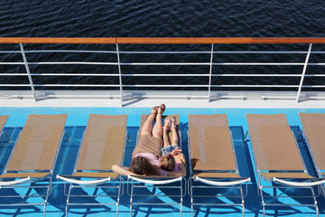 Top view of mother and daughter lying at deck-chair on ship