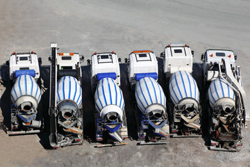 Six concrete mixer machines stand on asphalt at sunny day