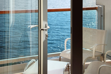 open door; glassy balcony with white chairs and table on liner
