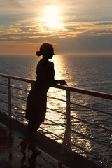 Fototapeta premium silhouette of woman looking into distance and standing on deck