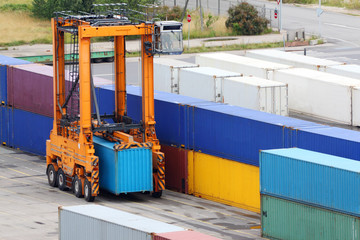 Large orange loader stands on asphalt and carries blue container