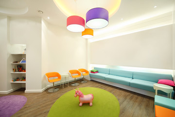 Empty lit room with soft couches, chairs and toys for children