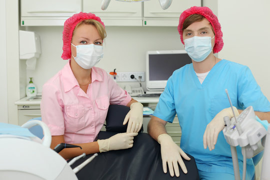 Two dentists in masks sit in cabinet of dental clinic