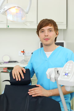 Dentist looks at camera in dental clinic and clings to chair for