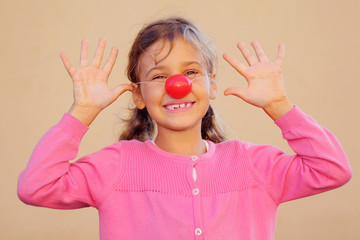 Beautiful girl wearing pink blouse with red clown nose smiles