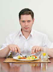 Handsome man eating with fork and knife