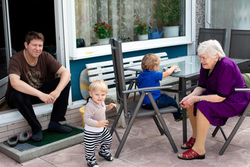 Grandmother, young man and two toddler boys on patio