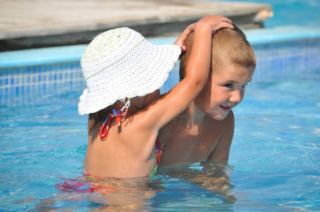 Smiling boy and little girl swimming in pool