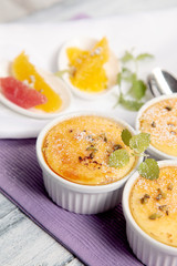 3 Schalen mit Creme Brulee dazu Zitrusfrüchte