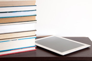 E-book reader and stack of books on a table