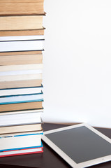 E-book reader and stack of books on a table