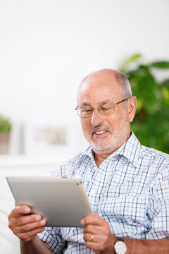 lächelner älterer mann schaut auf sein tablet