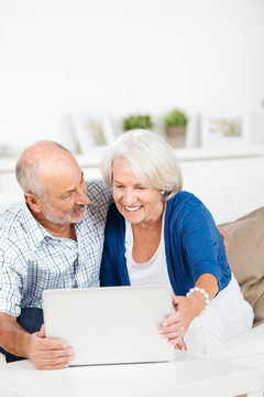 glückliches älteres paar schaut auf den laptop