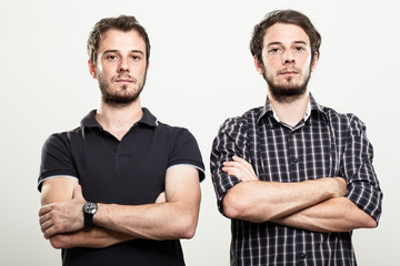 Two Serious Twins with Arms Folded - obrazy, fototapety, plakaty