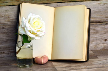 altes Buch und Rose auf altem Holz