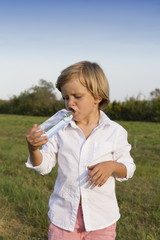 Young boy drinking water outdoors