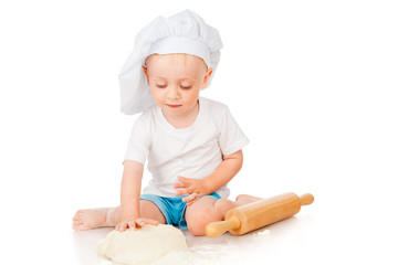 The little boy rolls the dough