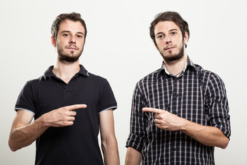 Two Serious Twins Pointing Each Other - obrazy, fototapety, plakaty