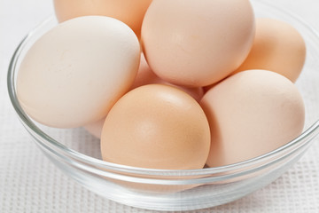 Fresh raw organic eggs in a glass bowl on the white cloth