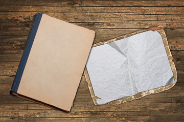 Old faded book and paper on a weathered wooden background