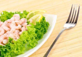 Delicious marinated shrimp in plate on bamboo mat