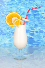 Delicious milk shake with fruit on table on blue sea background