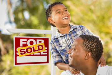 Mixed Race Father and Son In Front of Sold Real Estate Sign