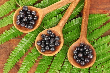 Tasty blueberries in wooden spoons on wooden background