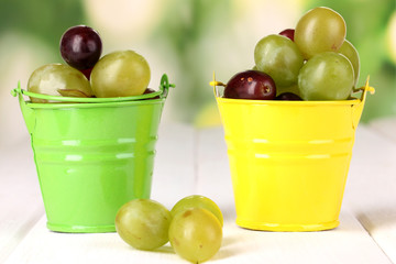 Ripe green and pink grapes in colorful pails