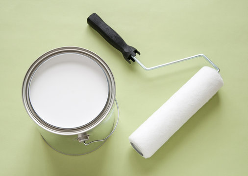 Can Of White Paint And Roller On Green Background