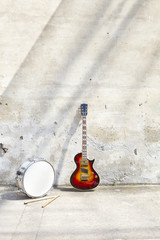 electric guitar and drum in front of a vintage wall