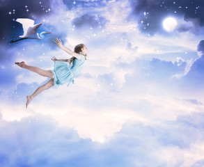 Little girl flying into the blue night sky