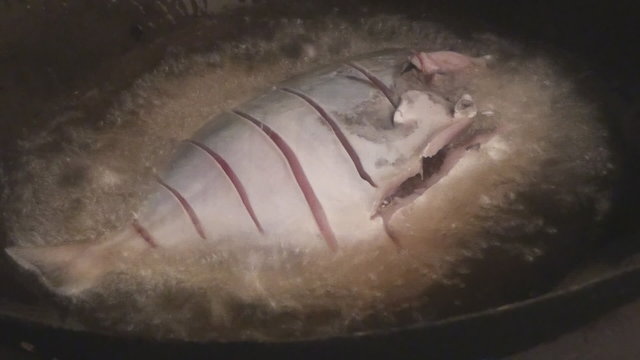 White fresh fish is being put into the half deep fry.