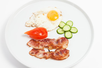 fried eggs, bacon and vegetables on white background