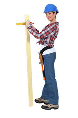 Woman measuring the width of a plank of wood