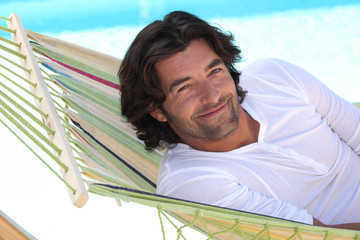 Man resting in hammock next to swimming pool