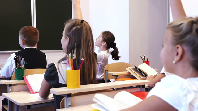 Schoolchildren raising their hands during the lesson
