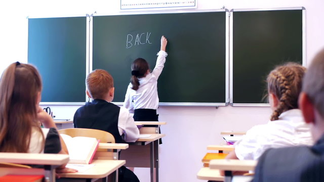 schoolgirl writing text back to school in the classroom