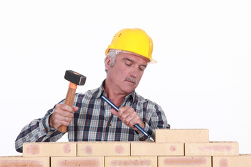 Worker using hammer and chisel on wall