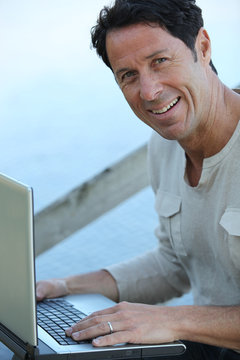 Man Sat Outdoors With Laptop Computer