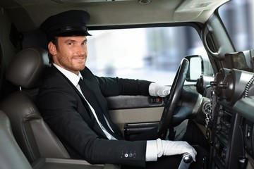 Handsome chauffeur driving limousine smiling - obrazy, fototapety, plakaty