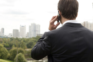 Businessman holding the phone standing in front the major cities