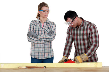 Man and woman using wood plane
